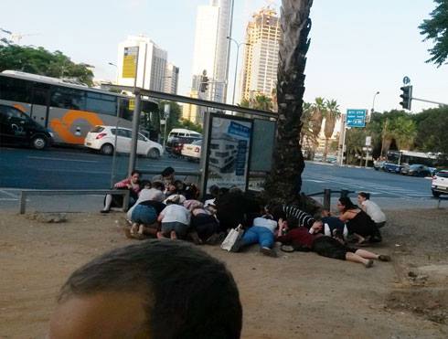 ハマスから発射されたミサイルが近づいたサイレン音によって、身をかがめるバス停の人々